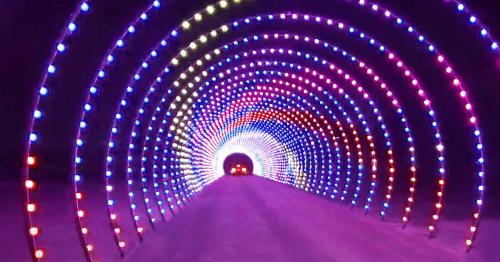 A colorful illuminated tunnel with vibrant lights in a spiral pattern, creating a festive and dynamic atmosphere.