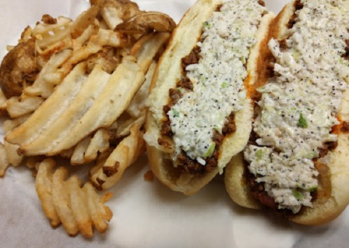 Two hot dog buns filled with a creamy mixture, served alongside a pile of crinkle-cut fries.