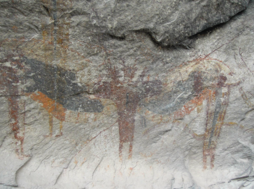 Ancient rock art depicting abstract figures and shapes in earthy tones on a textured stone surface.
