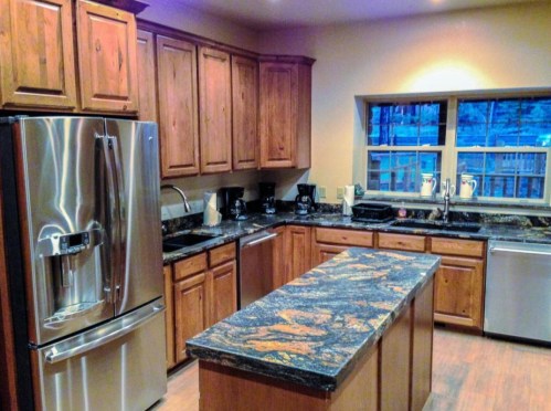 Modern kitchen with wooden cabinets, granite countertops, stainless steel appliances, and a large island.