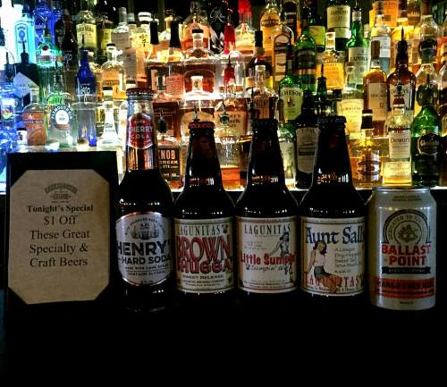 A bar display featuring various craft beers and a sign advertising $1 off specialty beers.