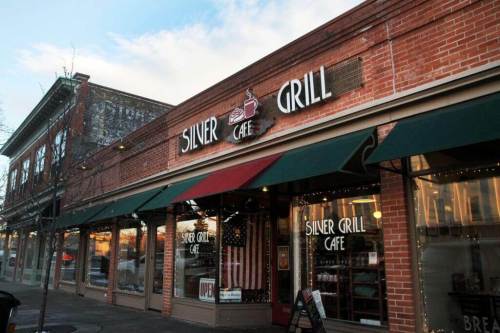 Exterior of Silver Grill Cafe, featuring a brick facade, green awnings, and large windows displaying the cafe's name.
