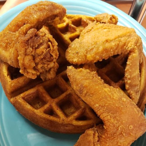 A plate of golden-brown waffles topped with crispy fried chicken wings.