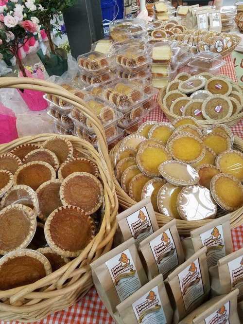 A display of assorted baked goods, including pies and cookies, arranged in baskets and trays at a market.