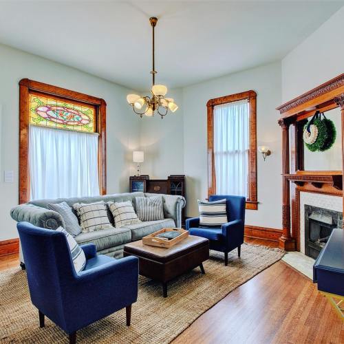 Cozy living room with a blue sofa, two armchairs, a coffee table, and stained glass windows, featuring warm wood accents.