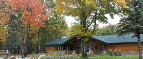 A cozy wooden lodge surrounded by colorful autumn trees and landscaping, showcasing fall foliage.
