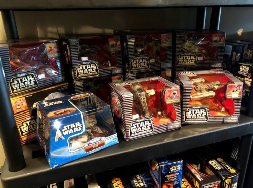 A shelf displaying various boxed Star Wars toy vehicles, featuring multiple designs and characters.