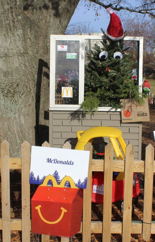 A festive display featuring a Christmas tree with googly eyes and a Santa hat, next to a McDonald's sign and toy car.