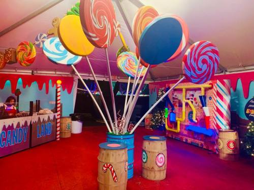 Colorful oversized lollipops in a festive Candy Land-themed tent with vibrant decorations and playful elements.