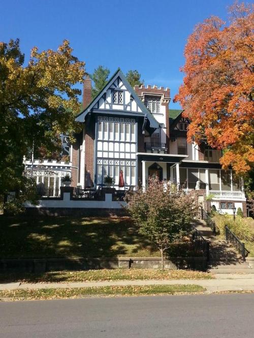A large, ornate house with a mix of architectural styles, surrounded by colorful autumn trees.