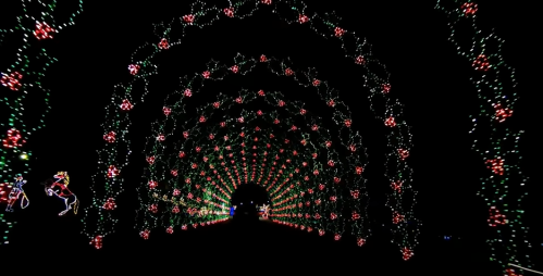 A colorful light tunnel with red and green decorations, creating a festive, spiraling pattern against a dark background.