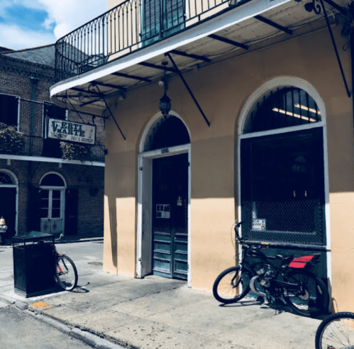 A charming street view of a building with green shutters, a sign, and bicycles parked outside in a vibrant neighborhood.