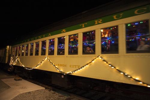 A decorated train car at night, illuminated with colorful lights and filled with people enjoying the festive atmosphere.