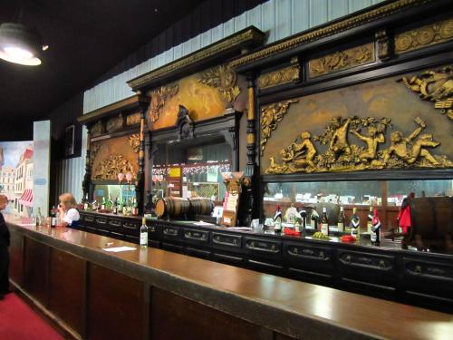 A vintage bar with ornate wooden decor, featuring intricate carvings and a long counter with various bottles displayed.