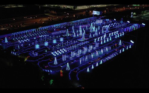 Aerial view of a festive light display featuring illuminated trees and decorations in various colors.