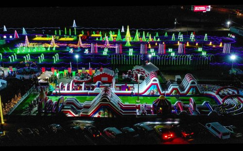 Aerial view of a colorful, illuminated amusement park with inflatable attractions and festive lights.