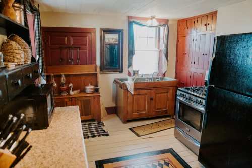 Cozy kitchen with wooden cabinets, a sink, stove, and rustic decor, featuring warm colors and natural light.