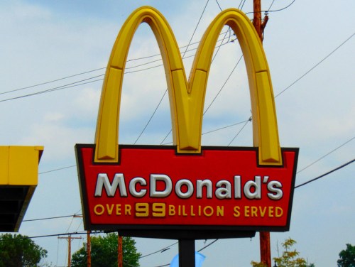 McDonald's sign featuring the iconic golden arches and the text "Over 99 billion served" against a cloudy sky.