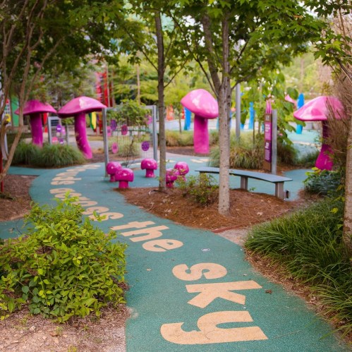 A whimsical park path with colorful mushroom sculptures and greenery, featuring the phrase "Let’s reach for the sky."