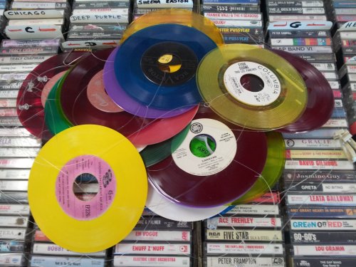 A colorful arrangement of vinyl records on a background of cassette tapes.