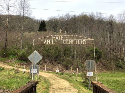 Sign for Hatfield Family Cemetery at the entrance, surrounded by trees and a dirt path.