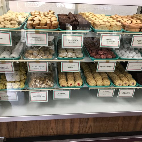A display case filled with various cookies and treats, each labeled with names and prices.