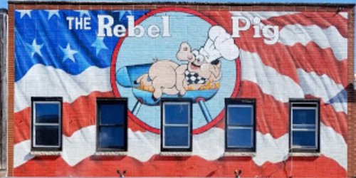 Mural of a pig chef grilling, with an American flag background and the text "The Rebel Pig."
