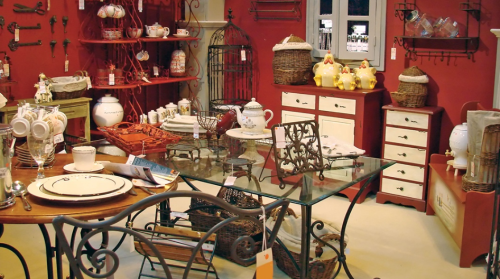 A cozy vintage shop interior featuring rustic furniture, decorative items, and a warm red backdrop.
