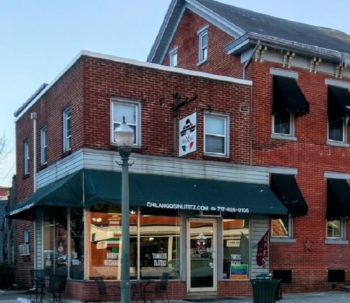 A brick building with a restaurant on the ground floor, featuring large windows and black awnings.