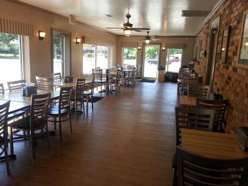 Interior of a restaurant featuring wooden tables, chairs, and large windows, with a warm, inviting atmosphere.