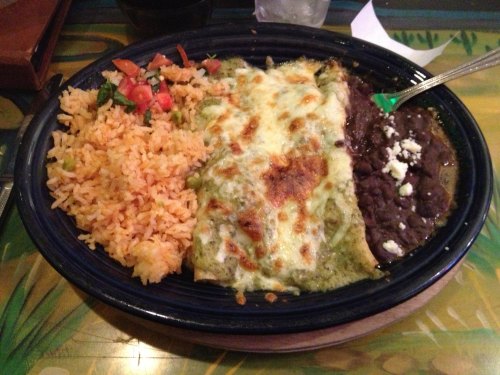 A plate of enchiladas topped with melted cheese, served with rice, black beans, and a side of fresh salsa.