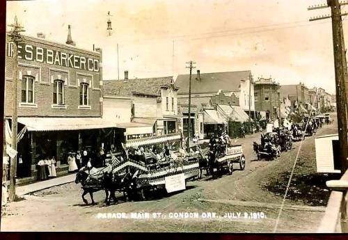 Historic parade on Main Street in Condon, Oregon, featuring decorated floats and buildings, dated July 3, 1910.