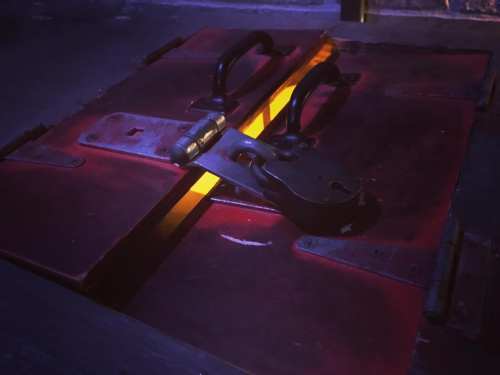 A locked wooden box with a glowing crack, set in a dimly lit environment.