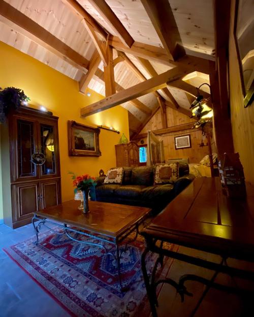 Cozy living room with wooden beams, a dark sofa, a coffee table, and warm yellow walls, featuring decorative accents.
