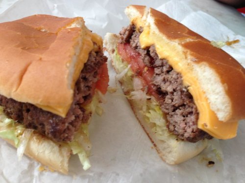 A close-up of a cheeseburger with lettuce, tomato, and a beef patty, served in a soft bun.