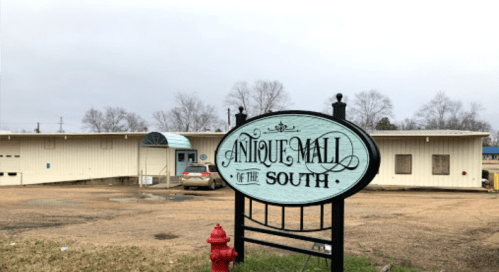 Sign for "Antique Mall of the South" in front of a single-story building on a cloudy day.