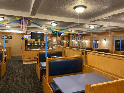 Interior of a diner decorated with colorful streamers and balloons, featuring booths and a welcoming atmosphere.