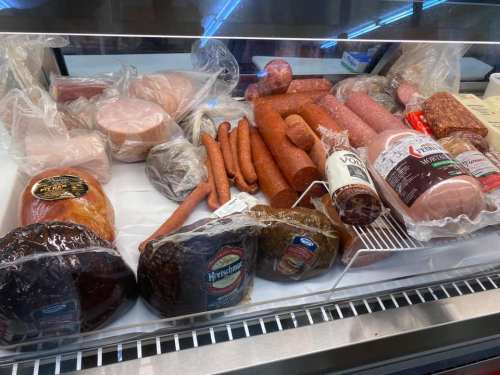 A display case filled with various types of packaged meats, including sausages, hams, and salamis.