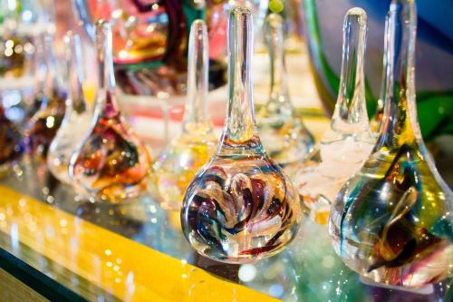 Colorful glass teardrop shapes with swirling patterns, displayed on a reflective surface.