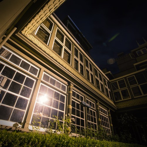 A low-angle view of a building at night, featuring large windows and a soft glow from a light source.
