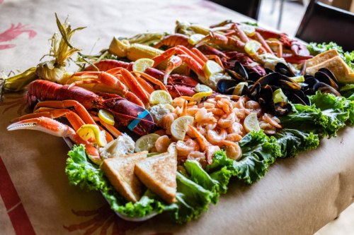 A vibrant seafood platter featuring lobster, crab, shrimp, mussels, lemon slices, and toasted bread on a bed of lettuce.