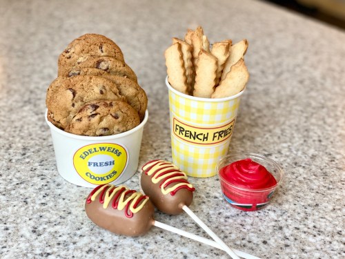 A display of cookies, French fries, and chocolate-covered treats with red icing on a countertop.