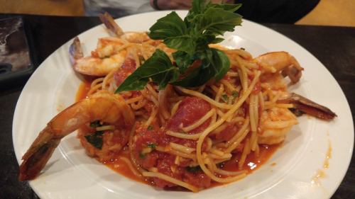 A plate of shrimp pasta topped with fresh basil in a rich tomato sauce.