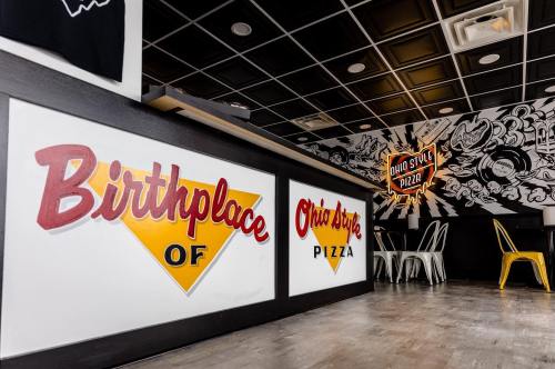 Interior of a pizza restaurant featuring "Birthplace of Ohio Style Pizza" signage and modern decor.