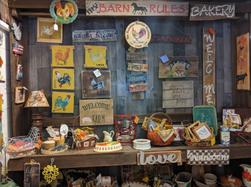 A rustic display of farm-themed decor, including signs, baskets, and various decorative items on a wooden shelf.