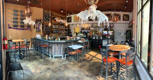 A cozy café interior with a bar, tables, and Halloween decorations, featuring a skeleton and cobwebs.