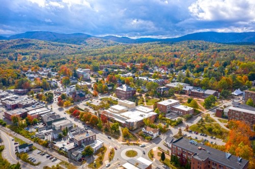 Aerial view of a vibrant town surrounded by colorful autumn foliage and mountains in the background.