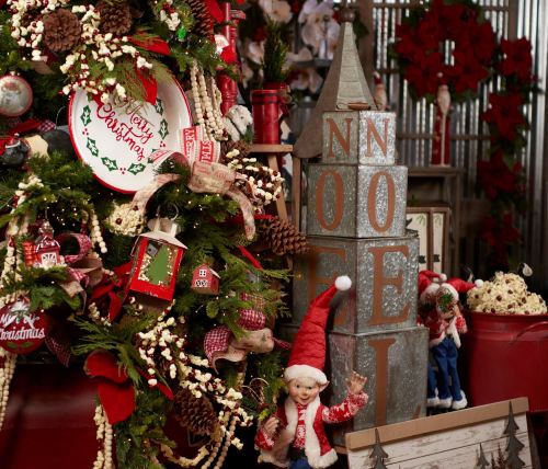 A festive display featuring a decorated Christmas tree, holiday signs, and cheerful elf dolls in a cozy setting.