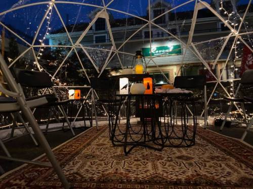 Cozy igloo-style seating area with string lights, a table, and decorative lanterns, set at night.