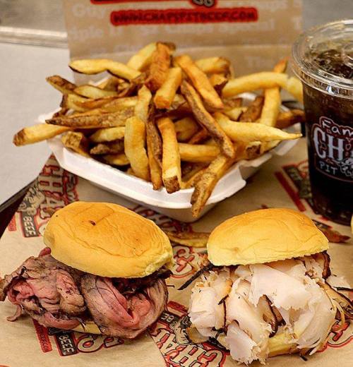 Two sandwiches with roast beef and turkey, served with a side of French fries and a drink.